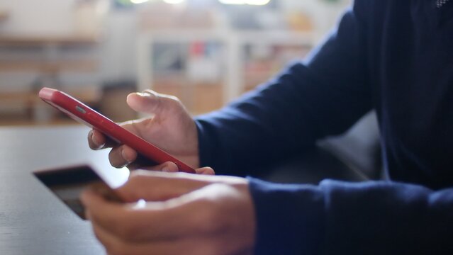 Person holding a mobile phone and credit card, using online banking application for secure e-commerce shopping, making digital payments and financial transactions