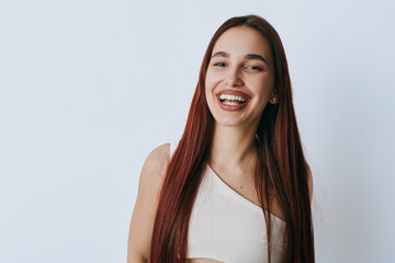 Young woman with long straight hair smiling and looking at camera on white background. Casual...