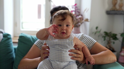 Baby sitting upright with mother’s support, early balance development, curious expression, interactive moment, parent-child bonding, trust, growth, care © Marco