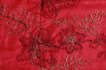 Floral embroidery pattern on red brocade fabric.
