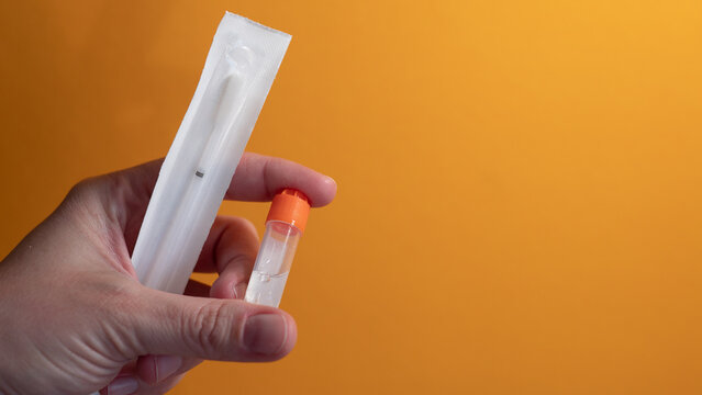 Hand holding home DNA testing kit with saliva sample tube for genetic ancestry test