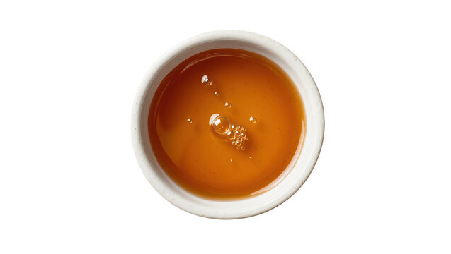 Isolated small white ceramic bowl containing sweet golden honey or maple syrup with bubbles.