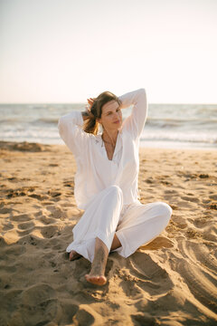 Beautiful 40 years old woman relaxing on the beach at sunset.