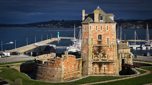 Aerial view of the Vauban Tower, a rosy stone sentinel guarding the harbor with boats, under a vast sky, Le Sillon, Camaret-sur-Mer, Bretagne, France.