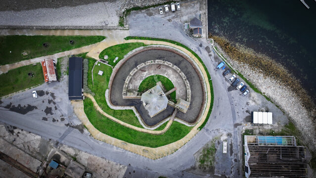 Aerial view of a circular fort with lush green grass in the center and dark water surrounding it, Camaret-sur-Mer, Bretagne, France.