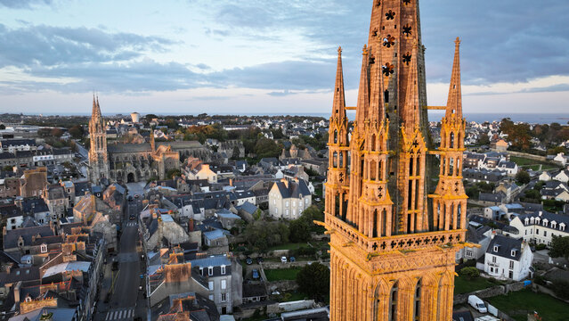 Aerial view of the ornate, gothic Kreisker chapel spire piercing the skyline, a testament to time amidst the town's rooftops, Saint-Pol-de-Leon, Bretagne, France.