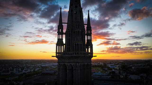 Aerial view of the spire of Saint-Pol-de-Leon Kreisker Chapel piercing the vibrant sunset sky, casting a dramatic silhouette against the colorful horizon, Saint-Pol-de-Leon, Bretagne, France.