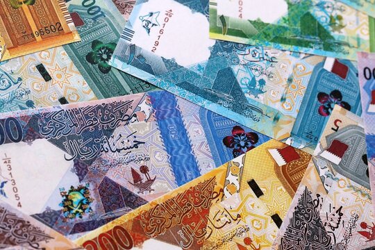 Qatari riyal money bills pile on table. Qatar banknotes of QAR currency close up.