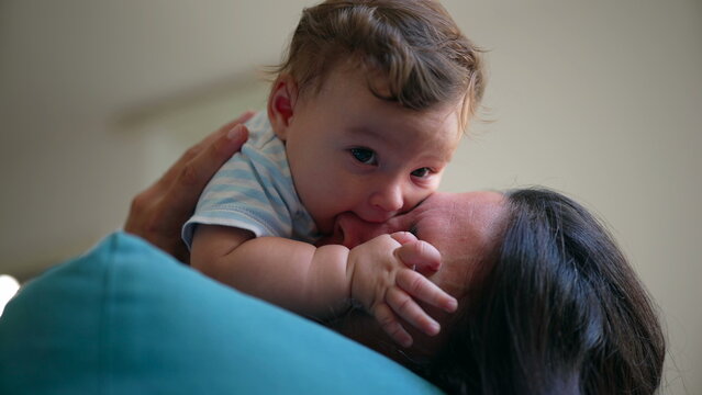 Baby resting on mother&rsquo;s chest, gently biting her cheek in a playful and affectionate moment, parent-child bonding, joy, trust, warmth, comfort, security