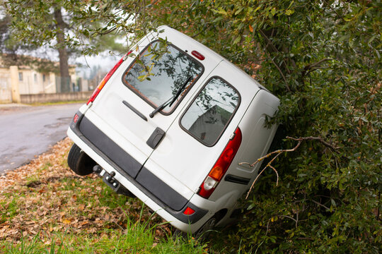 Voiture blanche utilitaire commercial tomb&eacute;e dans le foss&eacute; apr&egrave;s un accident en d&eacute;rapage dans un virage d'une petite route d&eacute;partementale.