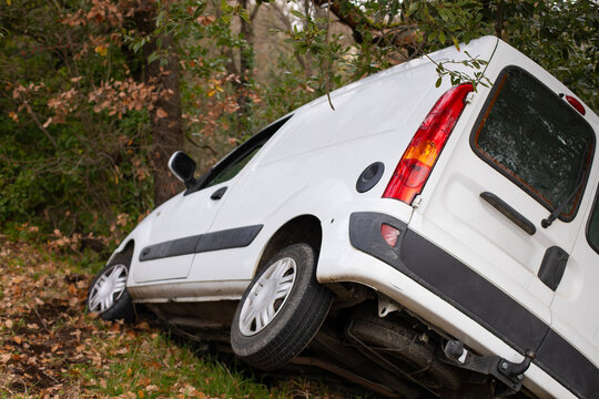 Voiture blanche utilitaire commercial tomb&eacute;e dans le foss&eacute; apr&egrave;s un accident en d&eacute;rapage dans un virage d'une petite route d&eacute;partementale de campagne.