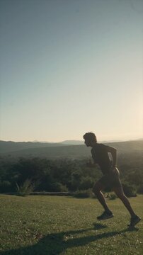 Silhouette of man running on grassy hill at golden hour sunset sunrise in slow motion
