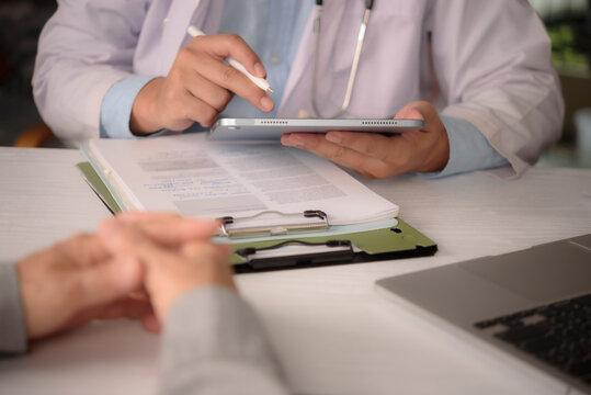 doctor using tablet to explain test result to patient during medical consultation. Physician showing digital medical record and discussing treatment plan at clinic. Modern patient care.