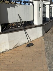A weathered, grimy broom leaning on the fence near an Orthodox church.