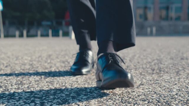 Front view, Close-up to the businessman in a black new classic shoes walks on the street. Legs of a businessman in fashionable shoes walking, outdoors. Business concept. Stylish men wears. Low angle