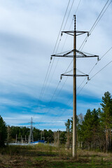 Obraz premium High Voltage Power Lines and Transmission Tower Crossing Rural Forest Landscape Under Blue Sky