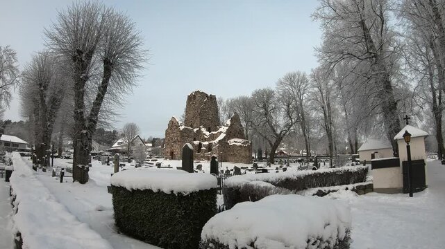 A serene winter scene featuring historic ruins surrounded by snow-covered trees and a tranquil atmosphere. The white landscape highlights the beauty of nature during the colder months.