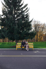 Naklejka premium Stylish young couple enjoying a romantic outdoor date under a towering evergreen tree