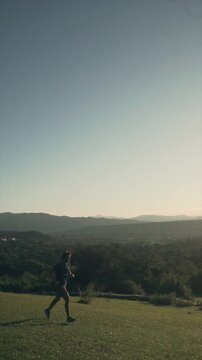 Silhouette of man running on grassy hill at golden hour sunset sunrise in slow motion