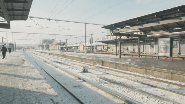 A tranquil winter morning at a train station, with snow covering the ground and tracks. The scene captures the essence of peaceful travel during the winter season, inviting commuters to embark on thei