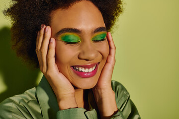 Beautiful woman embraces joyful moments with vibrant green makeup and a chic outfit