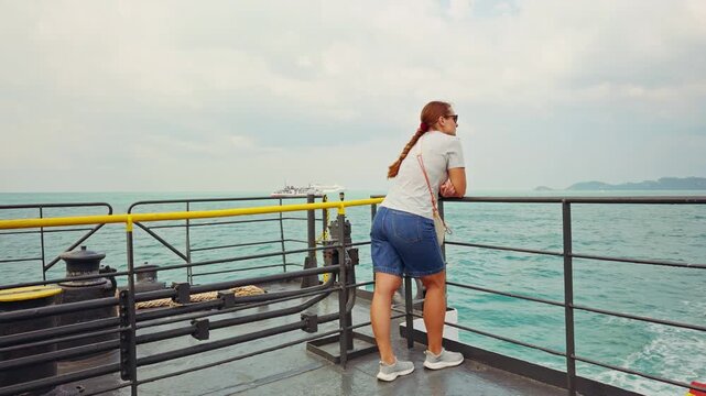 Rear View Of Woman On Ferry Deck Observing Sea And Distant Coastline During Island Crossing