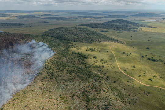 Aerial view of verdant plains meeting smoky horizons near Welgevonden Game Reserve, where nature's drama unfolds under a vast sky, Vaalwater, Limpopo, South Africa.