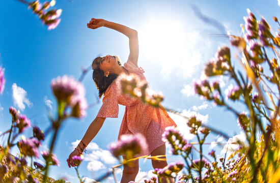 Summer mood. young and cheerful girl in summer dress posing against blue sky and flowers. beautiful girl dancing among flowers. girl enjoying summer.