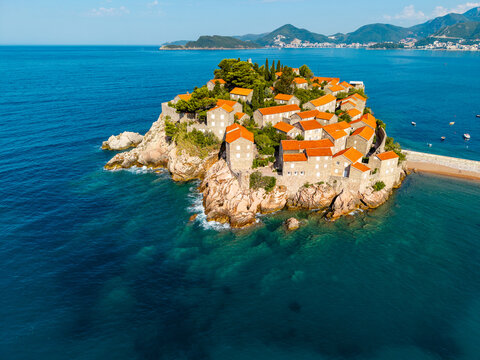 Aerial view of Sveti Stefan's terracotta rooftops nestled on a rocky islet against the azure Adriatic, a jewel of the Montenegrin coast, Sveti Stefan, Budva Municipality, Montenegro.