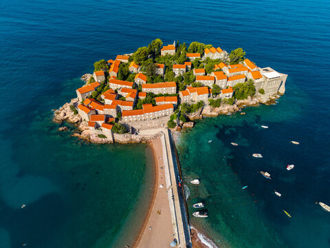 Aerial view of the terracotta rooftops of Sveti Stefan contrast beautifully with the turquoise Adriatic Sea, a fortified island connected by a narrow isthmus, Sveti Stefan, Montenegro.