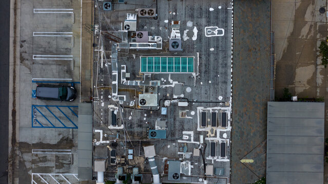 Aerial view of a rooftop with various mechanical structures casting shadows, creating a stark contrast against the weathered surface, West Hollywood, California, United States.