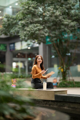 Woman working remotely outdoors using smartphone and tablet