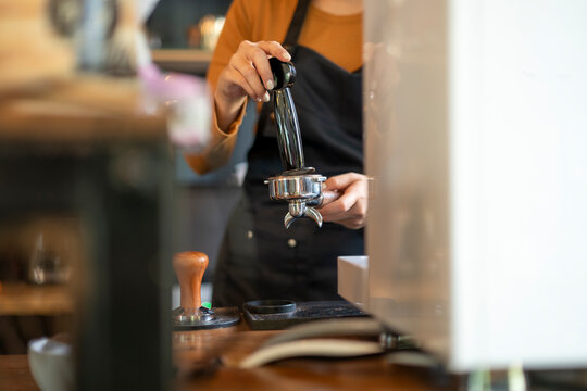 Barista tamping coffee in portafilter at cafe