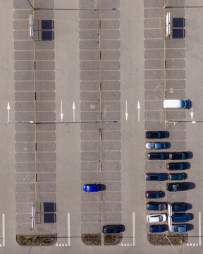 Aerial view of a parking lot, cars neatly arranged in designated spots, a structured dance of metal and asphalt, Warsaw, Masovian Voivodeship, Poland.