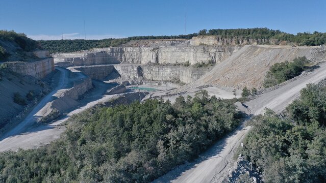 Aerial view of the vast, tiered quarry carved into the earth, revealing layers of rock and a small pool of water nestled within, Huntsville, Alabama, United States.