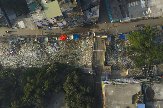 Aerial view of a river choked with plastic waste snaking through the city, contrasting with vibrant tarps and lush greenery, Dhaka, Dhaka Division, Bangladesh.