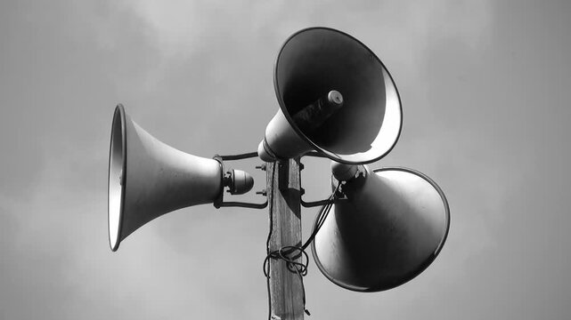 Megaphone tower with three speakers. Black and white. Clouds in background. HDV footage. HD.
