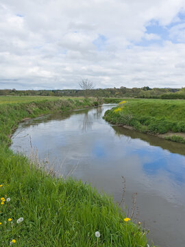 Old river arm of Dijle, with reflection of sky and clouds though a landscape near Louvain, Flanders, Belgium 