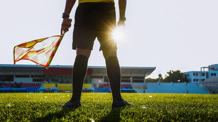 Low angle silhouette of a soccer linesman holding a flag against the sun © pixfly