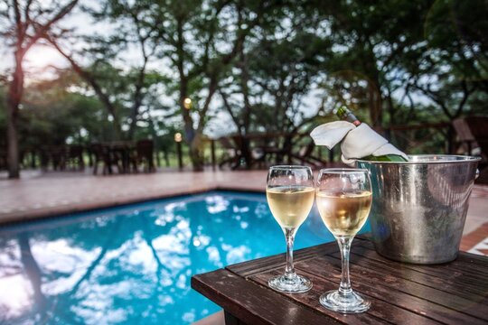 Gemini said

A crystal glass of champagne and wine sit on a clean table by the pool, reflecting a celebration at a luxury restaurant bar during a wedding party or holiday dinner