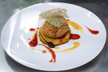 Gourmet dessert with breaded ice cream ball served on pineapple slice with fruit sauces