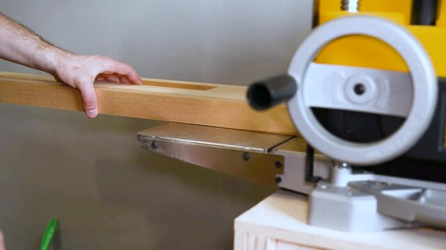 Carpenter shaping wooden block on planer thicknesser jointer machine in workshop.