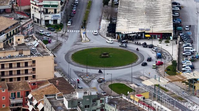 Aerial drone view of a busy roundabout with an anchor monument and traffic flow in Corfu town near the port, urban transportation infrastructure