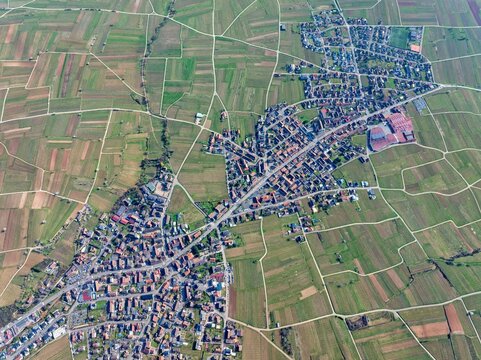 Aerial view of a tapestry of verdant fields and quaint rooftops, where the linear roads cut through the scene, Mittelwihr, Grand Est, France.