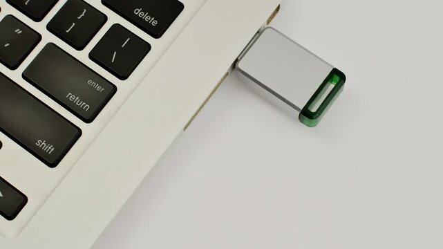 Detail of a USB drive next to a laptop, representing portable technology and fast data transfer.