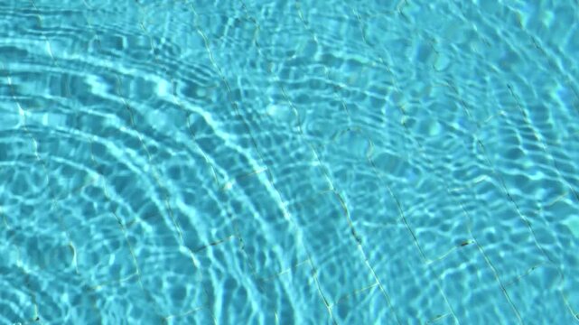 Abstract swimming pool water footage with sunlight reflections and soft ripples moving over a tiled bottom. Clean summer background for advertising, travel, spa and design projects.