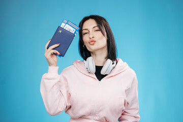 Naklejka premium Smiling young traveler woman holding passport with flight tickets on clean background. Travel and holiday concept. 