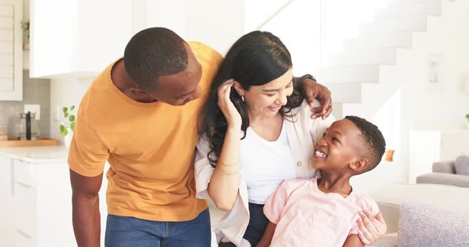 Diverse family dad leaning in cuddling child in kitchen by sofa mother tucking hair posing smiling