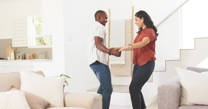 Diverse couple holding hands, starting coordinated steps on raised step near sofa, practicing dance