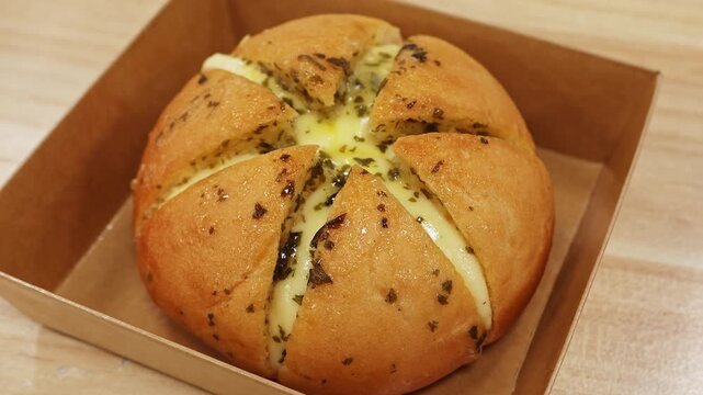 Cheese cream bun with herbs bakery closeup. Fresh savory pastry in paper box on table. Concept of bakery snack, comfort food, takeaway meal and street bakery product.